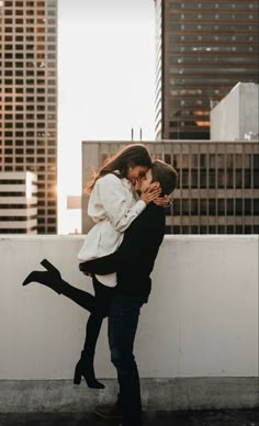 a man and woman embracing each other in front of tall buildings