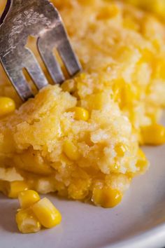 a fork that is on top of some corn casserole with another dish in the background