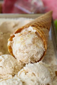 two scoops of ice cream sitting in a container with an apple behind it,