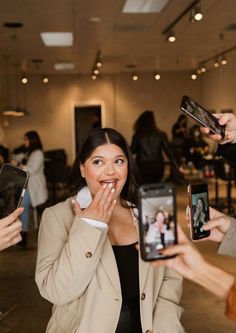 a woman holding up two cell phones to her face while another person takes a selfie