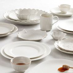 a table topped with white dishes and plates covered in saucers, cups and saucers