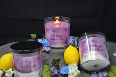 three candles sitting on top of a table next to lemons and flowers