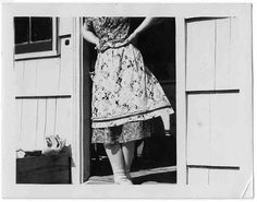 an old photo of a woman standing in the doorway