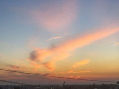 the sun is setting over a city with power lines and telephone poles in the foreground