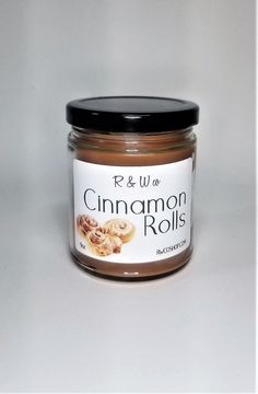 a jar of cinnamon rolls sits on a white surface with a black lid and the label reads r & w cinnamon rolls