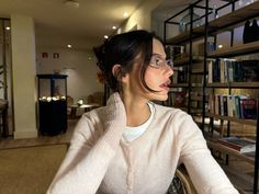 a woman sitting at a table in front of a book shelf