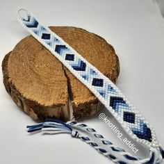 a blue and white beaded bracelet sitting on top of a piece of wood next to a rope