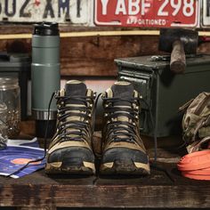 a pair of hiking boots sitting on top of a wooden table next to other items