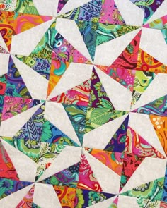 the colorful quilt is made up of many different colors and shapes, including white triangles