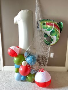 there are many balloons and balls in the room next to an object that looks like a fish