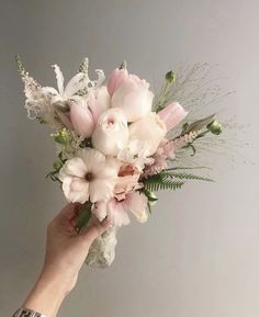 a person holding a bouquet of flowers in their hand with the other hand on it