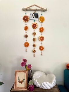 a wall hanging made out of oranges and other items on a table next to a blue couch