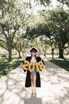 a woman with purple hair is holding balloons in the shape of numbers