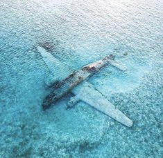 an airplane that is floating in the water near some sand and blue water with no one on it