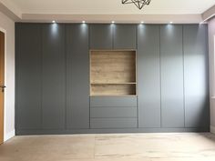 an empty room with grey painted walls and wooden shelves on the wall, in front of a light fixture