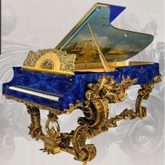 an ornate blue and gold grand piano with artwork on the top, in front of a white background