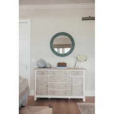 a white dresser and mirror in a room with hardwood floors, rugs and walls