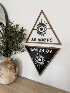 there is a plant in a vase next to a wall sign that says as above