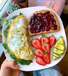 a person holding a plate with food on it and fruit in front of the plate