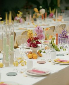 the table is set with plates, glasses and vases filled with flowers on them