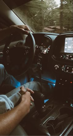 a man sitting in the driver's seat of a car with his hands on the steering wheel