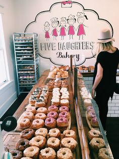 a woman standing in front of a counter filled with donuts and other pastries