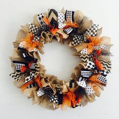 a wreath made out of burlocks and mesh with orange, black and white bows