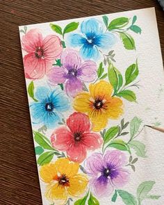 a watercolor painting of colorful flowers on white paper with green leaves and pencils