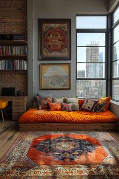 an orange couch in front of a window with bookshelves and pictures on the wall