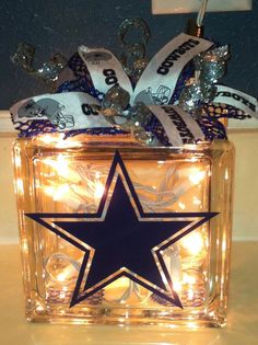 a lighted glass box with a star on the front and ribbon tied around it's sides