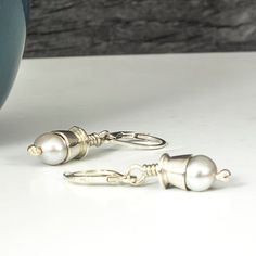 These elegant handmade sterling silver dangle pearl earrings feature beautiful white pearl beads. The pearls hang from lever back closures for a secure fit. Perfect for any occasion, these timeless earrings will be an instant classic in any jewelry collection. Materials: sterling silver, pearls Finish: comes with patina Closure: lever back Fabrication time: 1 week Shipping: free ground advantage shipping within the USA with tracking and insurance included. Care: it is always best to prevent gett Dangle Pearl Earrings, Timeless Earrings, Pearl Dangle Earrings, Sterling Silver Dangle Earrings, Pearl Earrings Dangle, Silver Earrings Dangle, Silver Pearls, The Pearl, Handmade Sterling Silver