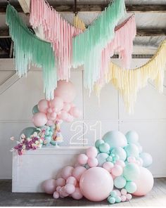 balloons and streamers are hanging from the ceiling in front of a number twenty sign