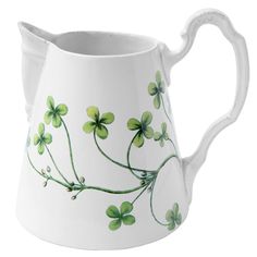 a white pitcher with four leaf clovers painted on it