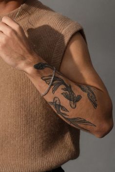 a man with a tattoo on his arm holding a cell phone in his right hand