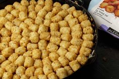 a pan filled with tater tots next to a bag of chicken nuggets