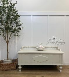 a white dresser next to a potted tree