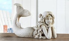 a statue of a mermaid laying on top of a wooden table