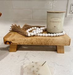 a candle and some white beads on a wooden stand next to a tile counter top