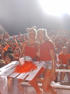 two women in red shirts and silver shorts standing next to each other at a football game