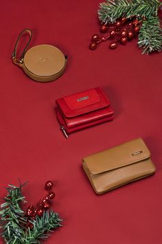 three different types of purses on a red surface next to christmas decorations and ornaments