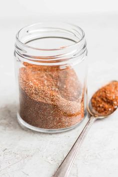 a glass jar filled with spices next to a spoon