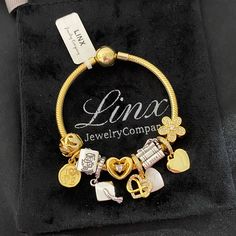 a gold bracelet with charms on it sitting in a black velvet bag that says lina jewelry company