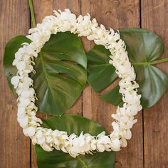 white flowers and green leaves arranged in the shape of a letter o on a wooden surface