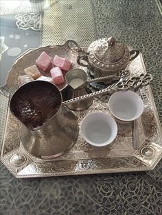 a silver tray topped with cups and saucers filled with different types of desserts