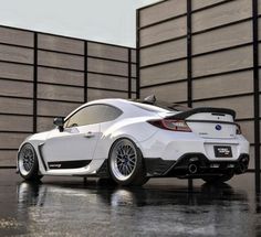 a white sports car parked in front of a wall