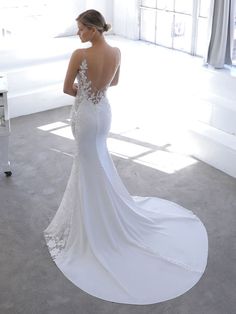 a woman in a white wedding dress is looking at the back of her gown,