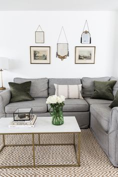 a living room with gray couches and white coffee table in front of the sectional