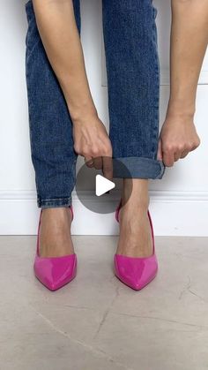 a woman wearing pink high heels standing next to a wall