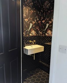 a bathroom with a sink and black tiled walls