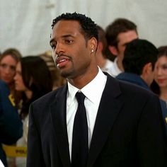 a man wearing a suit and tie standing in front of a crowd